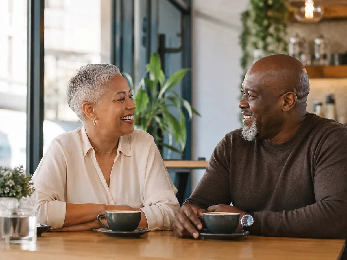 Two mature South African people enjoying a relaxed coffee date and laughing together.